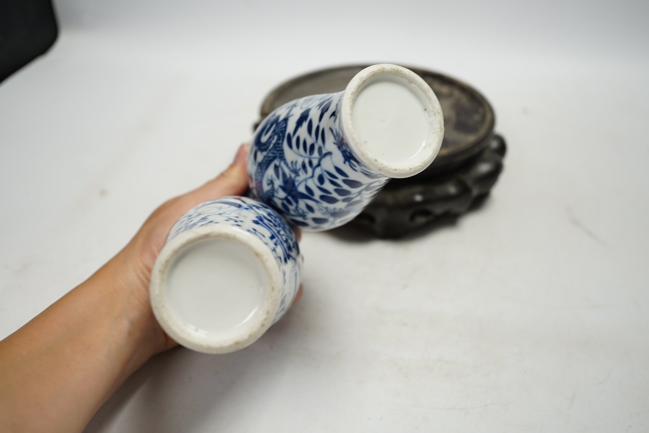 Two Chinese blue and white vases, late 19th century, and a carved hardwood vase stand, vases 15cm high. Condition - one vase good, one with hairline crack, stand poor